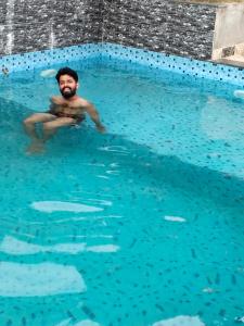 a man sitting in a pool of blue water at Padikkal Bungalow in Vayittiri +18 photos