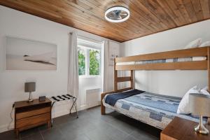 ein Schlafzimmer mit Etagenbett und Holzdecke in der Unterkunft Les Chalets Baie Cascouia in Larouche