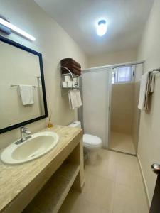 une salle de bain avec un lavabo, des toilettes et un miroir dans l'établissement Peach35 Apartamento centrico, 5 min de la playa, à Cancún