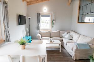 a living room with a white couch and a table at Peenehof Köppen - Ferienwohnungen & Schlaffässer in Jördenstorf
