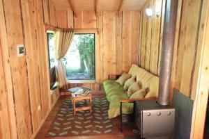 a room with a green couch in a wooden house at Cabañas Los Alamos Neltume in Neltume