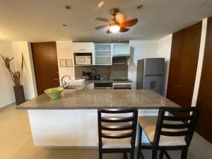 a kitchen with a large island with two bar chairs at Luxury Condo Mareia Ixtapa 101 in Ixtapa +3 photos