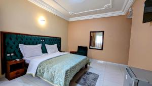 um quarto com uma cama grande com cabeceira verde em ALICIA HOTEL em Douala