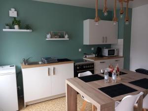 a kitchen with a wooden table and white cabinets at Le Camus in Belonchamp