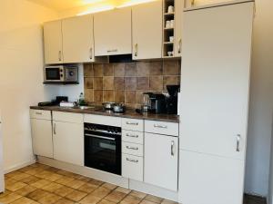 a kitchen with white cabinets and a stove at App Blaue Welle in Morsum +11 photos