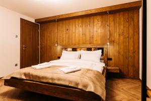 a bedroom with a large bed with wooden walls at Grand Chalet Lacu Rosu in Lacu Rosu