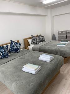 two beds in a room with towels on them at JR Shin-Osaka 30s, Direct to Kansai Airport 關西空港直達,Shinkansen to Tokyo, Tokyo & Nagoya, Universal Studio 16 mins, Umeda 6 mins, Kyoto 25 mins, Early Check-In in Osaka
