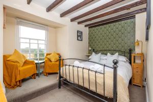 a bedroom with a bed and two chairs and a window at Unicorn Inn in Deddington