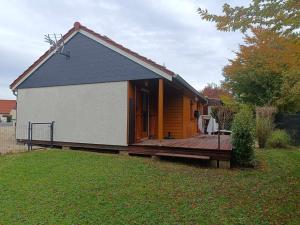 a small house with a wooden deck in a yard at La Cachotière du Lac in Giffaumont-Champaubert
