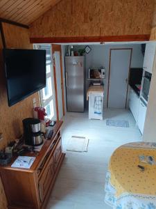 a living room with a television and a kitchen at La Cachotière du Lac in Giffaumont