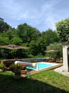 einen Pool in einem Garten mit Stühlen und einem Sonnenschirm in der Unterkunft Les Terrasses, gîtes en Cévennes in Saint-Jean-de-Valériscle