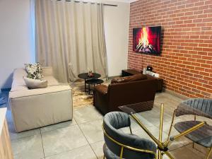 un soggiorno con divani e un muro di mattoni di 7 Elizabeth Place - Beautiful self catering 1 bedroom unit next to Kyalami Racetrack with free WiFi - swimming pool gym and restaurant - Perfect for a couple in Midrand Waterfall a Midrand