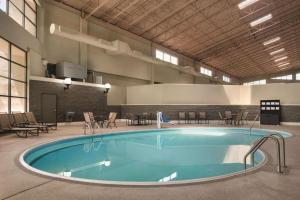 a large pool in a building with tables and chairs at Wyndham Garden Conference Center Champaign - Urbana in Champaign