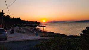 a sunset over a beach with umbrellas and the ocean at Marinas house in Vaia +2 photos