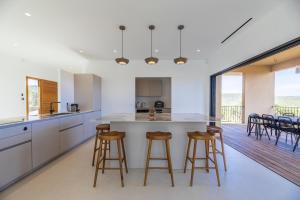 una cucina con mobili bianchi e sgabelli da bar di Villa Paola a Pianottoli-Caldarello