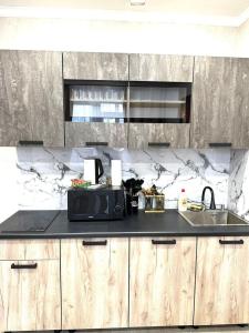 a kitchen with a counter with a microwave and a sink at Жк Панель центр in Fëdorovka +3 photos