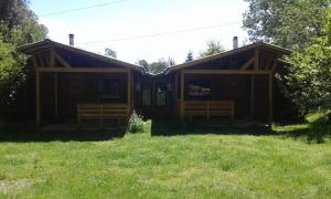 a wooden cabin with a grassy yard in front of it at Cabañas Los Alamos Neltume in Neltume