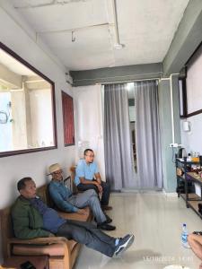 three men sitting on chairs in a room at Duhthang Run Backpackers Inn in Āīzawl