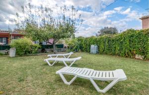 two white benches sitting in the grass in a yard at Awesome Home In Sant Miquel De Fluvià in San Miguel de Fluviá