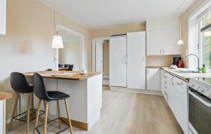 Una cocina con gabinetes blancos y una mesa y sillas. en 3 Bedroom Gorgeous Home In Aakirkeby, en Åkirkeby