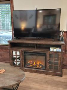 ein Wohnzimmer mit einem Kamin und einem TV darüber. in der Unterkunft Dovetail Den - Tranquil with Hot Tub and Air Conditioning in Ashford