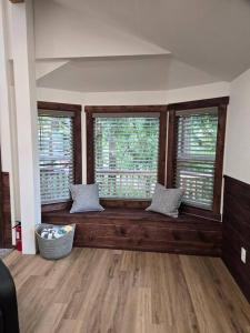 ein Wohnzimmer mit zwei Fenstern und einer Holzbank in der Unterkunft Dovetail Den - Tranquil with Hot Tub and Air Conditioning in Ashford