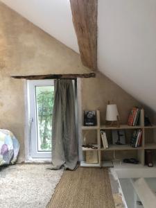 Cette chambre mansardée dispose d'une fenêtre et d'une étagère. dans l'établissement La Petite Maison, à Survilliers