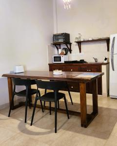 a kitchen with a wooden table with chairs and a refrigerator at El Colonial Departamentos in Cafayate