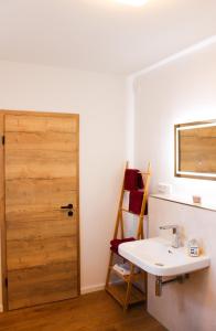 a bathroom with a sink and a wooden door at Ferienwohnung Repetal in Attendorn