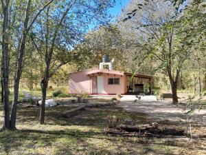 a small pink house in the middle of trees at La Casita del Vivero in Casa Grande