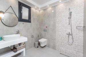 een badkamer met een wastafel, een toilet en een spiegel bij Ionas Apartments 1 in Nea Skioni +15 foto's
