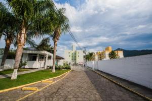 a street with palm trees and a white wall at Apartamento completo ao lado da Arena Opus in Estêvão