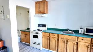 a kitchen with wooden cabinets and a white stove top oven at Prince Motel in Prince George +11 photos