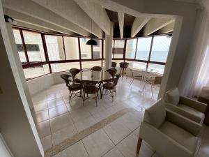 una sala da pranzo con tavolo, sedie e finestre di Apartamento quadra mar a Meia Praia