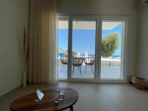 a living room with a sliding glass door with a view of the ocean at Tamaris Suites in Karpathos