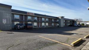 a hotel with cars parked in a parking lot at Prince Motel in Prince George