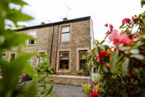 a brick house with red flowers in front of it at Quirky comfort cottage in Haslingden