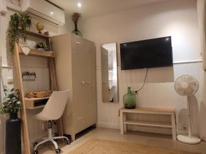 a living room with a tv and a chair and a desk at "COZY LOFT", TERRACE, PARKING and SWIMMING POOL in Málaga