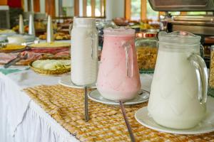 Drei Milchbehälter stehen auf einem Tisch. in der Unterkunft VELINN Áustria Hotel Monte Verde in Monte Verde