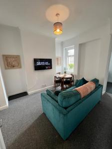 a living room with a blue couch and a table at Live Like a Local in Barry, 4-Bed Home Near the Beach, Dog-Friendly, with all the Gavin & Stacey Charm! in Barry