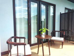 a table and two chairs in a room with windows at Luang Prabang Meunna Hotel in Luang Prabang