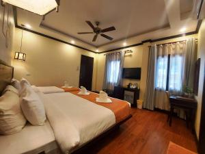 a bedroom with a large bed with a ceiling fan at Luang Prabang Meunna Hotel in Luang Prabang