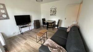 a living room with a couch and a table and a television at Studio avec jardin centre ville Cabourg La Roseraie in Cabourg