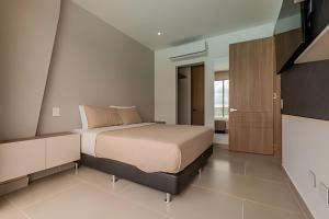 ein Schlafzimmer mit einem Bett und einem Fernseher in der Unterkunft Lujoso A Estrenar/Oasis Laguna Cristalina 2BR in Los Arrayanes