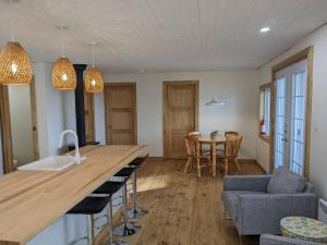 a kitchen and living room with a counter and a table at Chic refuge sur le bord de l'eau et des sentiers motoneiges! in Saint-Honoré +16 photos
