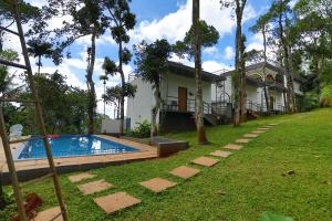 a house with a swimming pool in front of a yard at Roots Munnar in Anachal