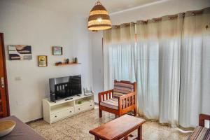 a living room with a television and a chair at apartamento famara 4 in Famara +3 photos