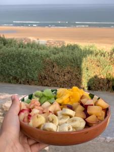 a person holding a bowl of fruit in a bowl at The berber beach in Aghnajane +39 photos