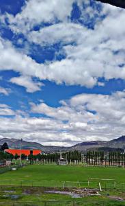 a green field with a sky with clouds at casa de campo in Ibarra