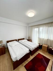 a bedroom with two beds and a large window at Pensiunea Cezara in Bacău +9 photos